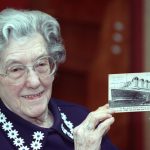 EVA HART SURVIVOR OF THE SINKING OF THE TITANIC DISPLAYS A POSTCARD OF THE SHIP IN LONDON.